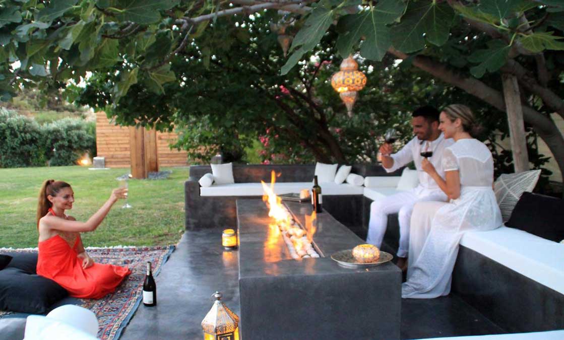 Φίλοι σηκώνουν τα ποτήρια τους γύρω από το firepit στον κήπο