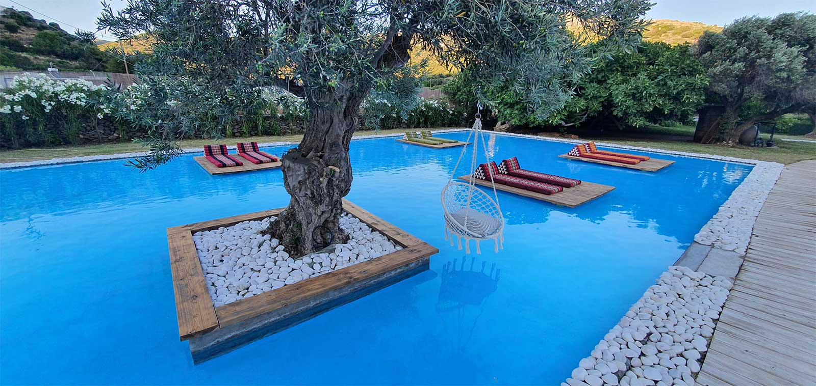 Hanging swing over the pool with colourful Thai cushions on floating loungers