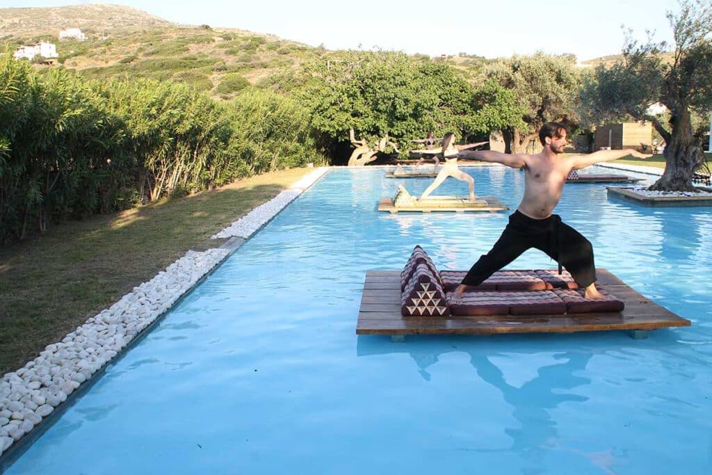 Warrior II pose on a floating wooden platform in the pool at Ow Andros, Andros Island
